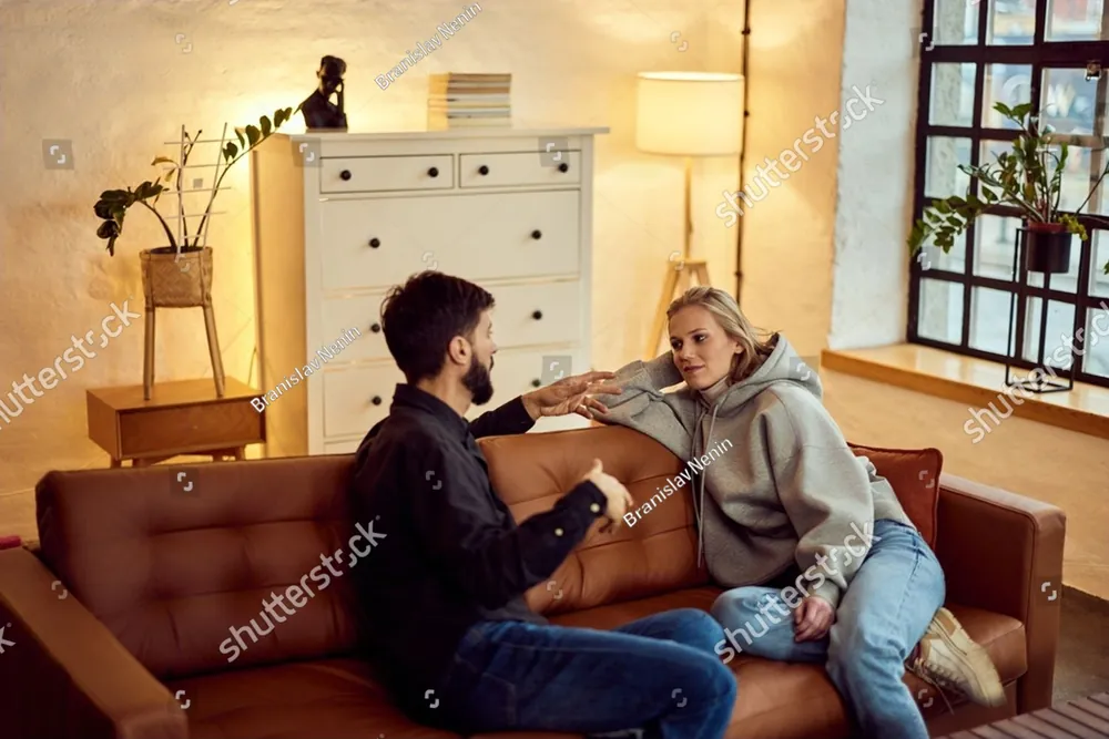A couple talking together on a leather sofa in a warm living room