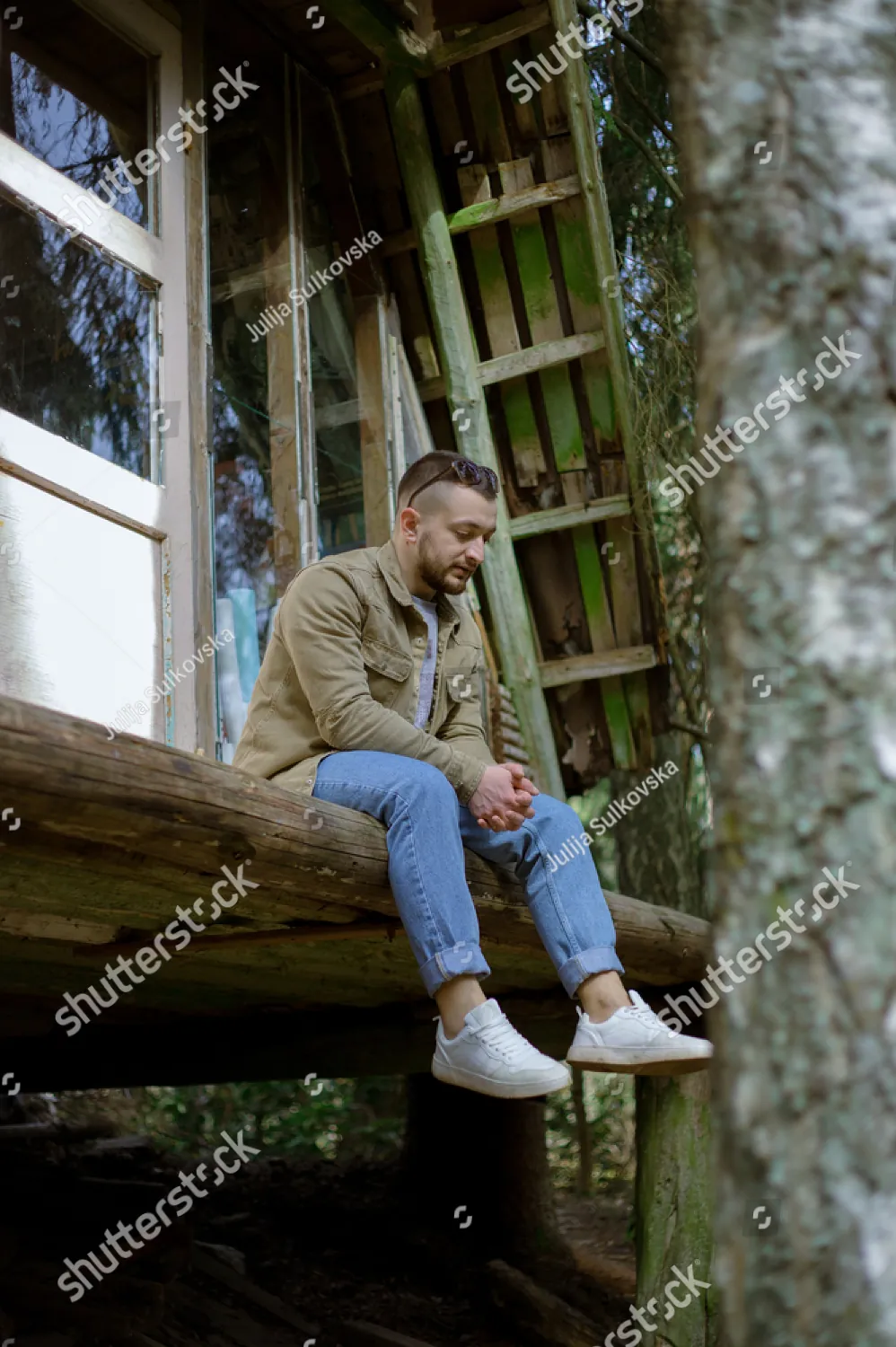 A man sitting on a wooden platform among the trees