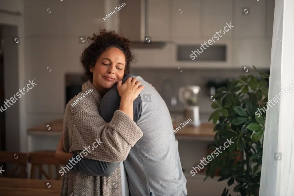 A woman embracing a man in their kitchen