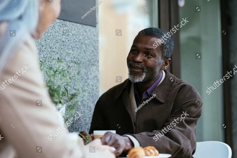 An older man smiling across a cafe table