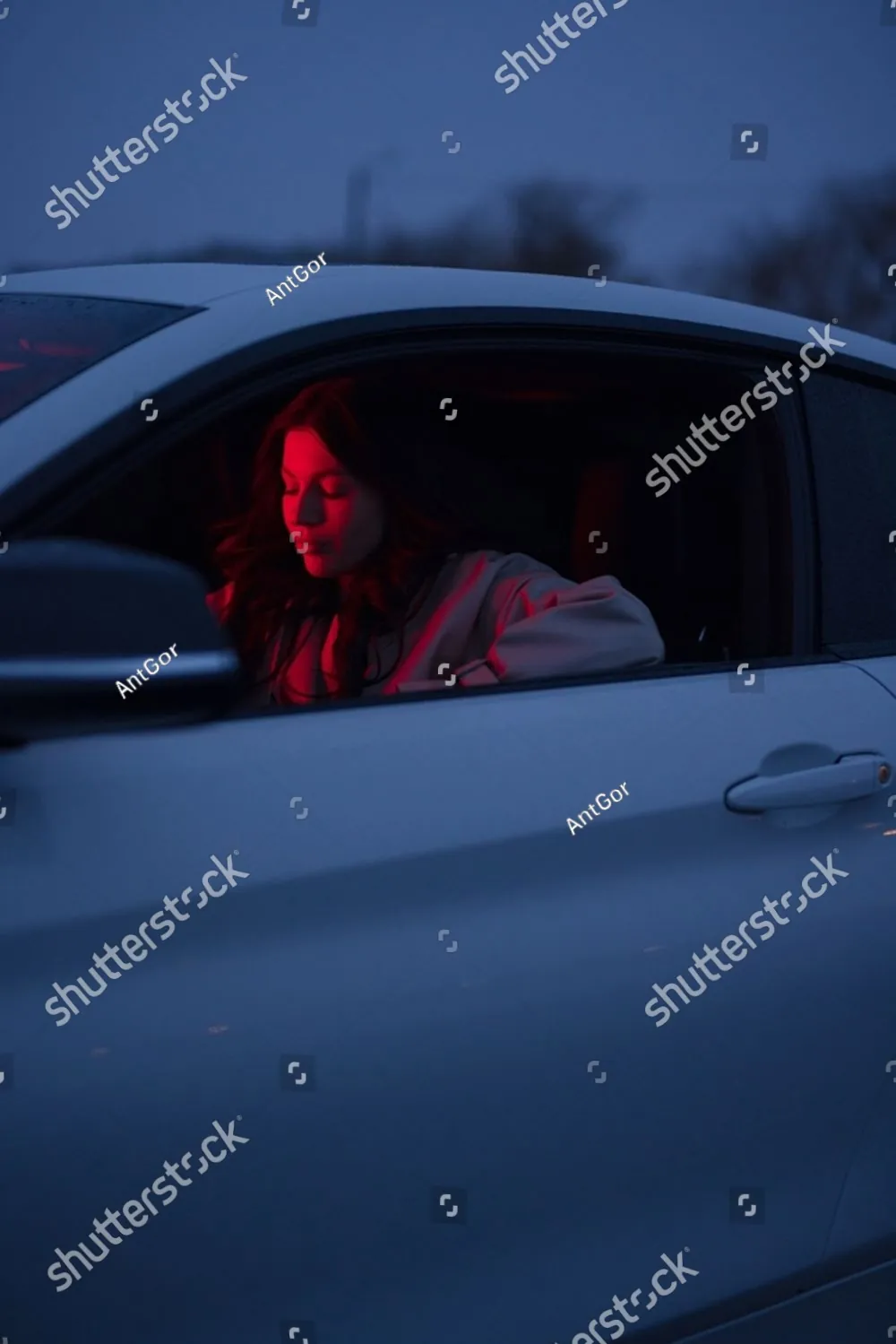A woman sitting alone in her car at night