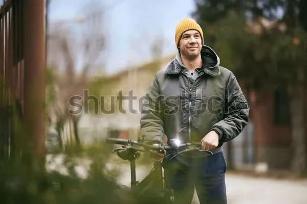 A man in a yellow beanie standing on a city street