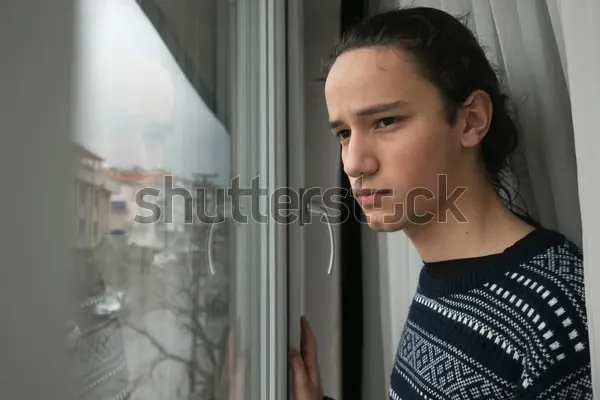 A teenage boy looking out of a window