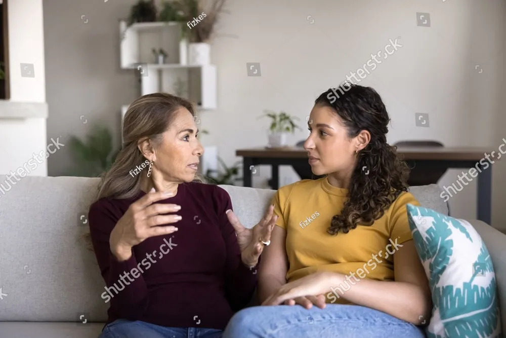 A mother and her teenage daughter talking on the sofa